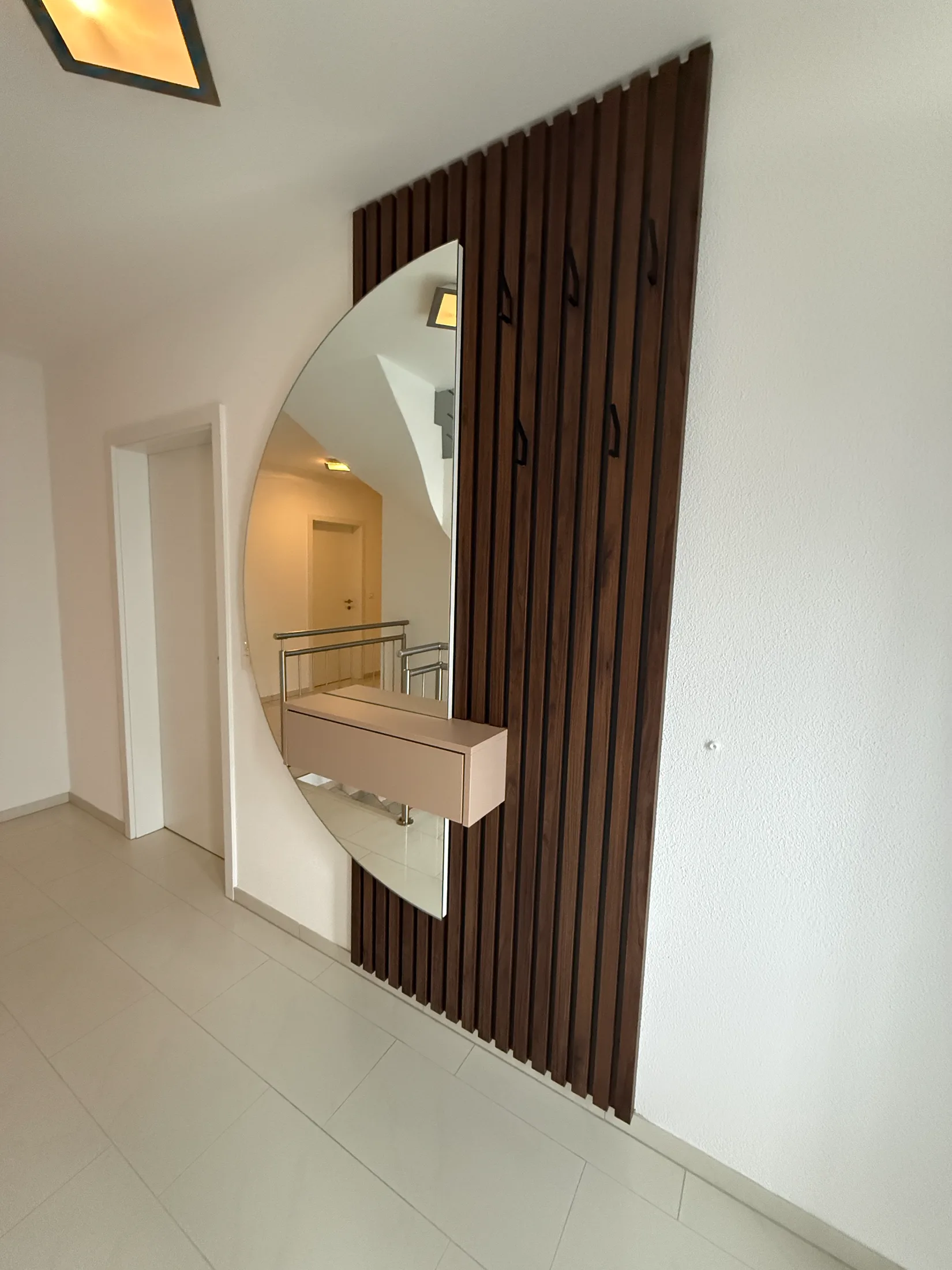 Eingangsbereich mit Holzlamellen-Wand, großem Spiegel und schwebender Konsole