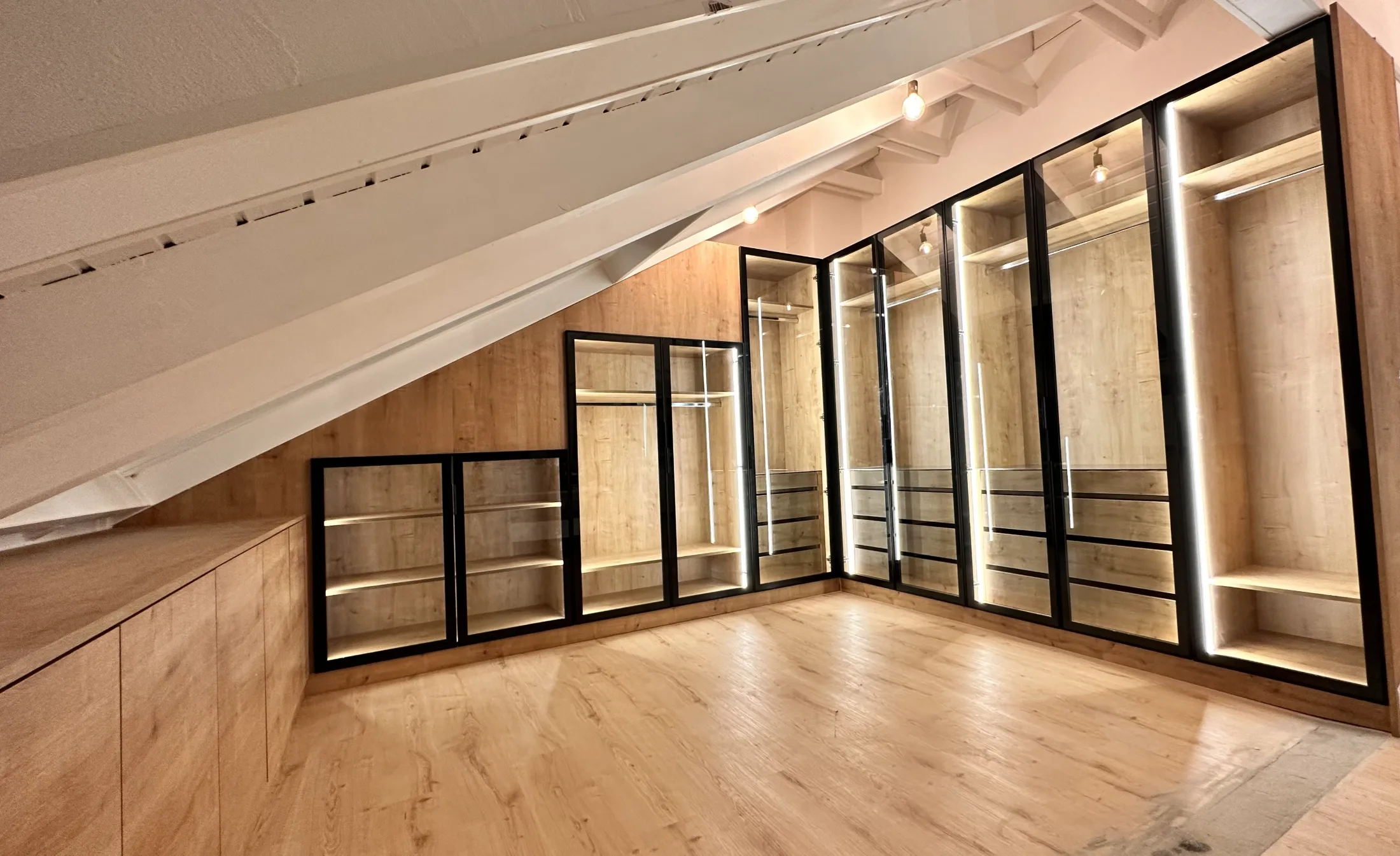 Individueller Glasschrank unter Dachschräge mit LED-Beleuchtung und Holzstruktur