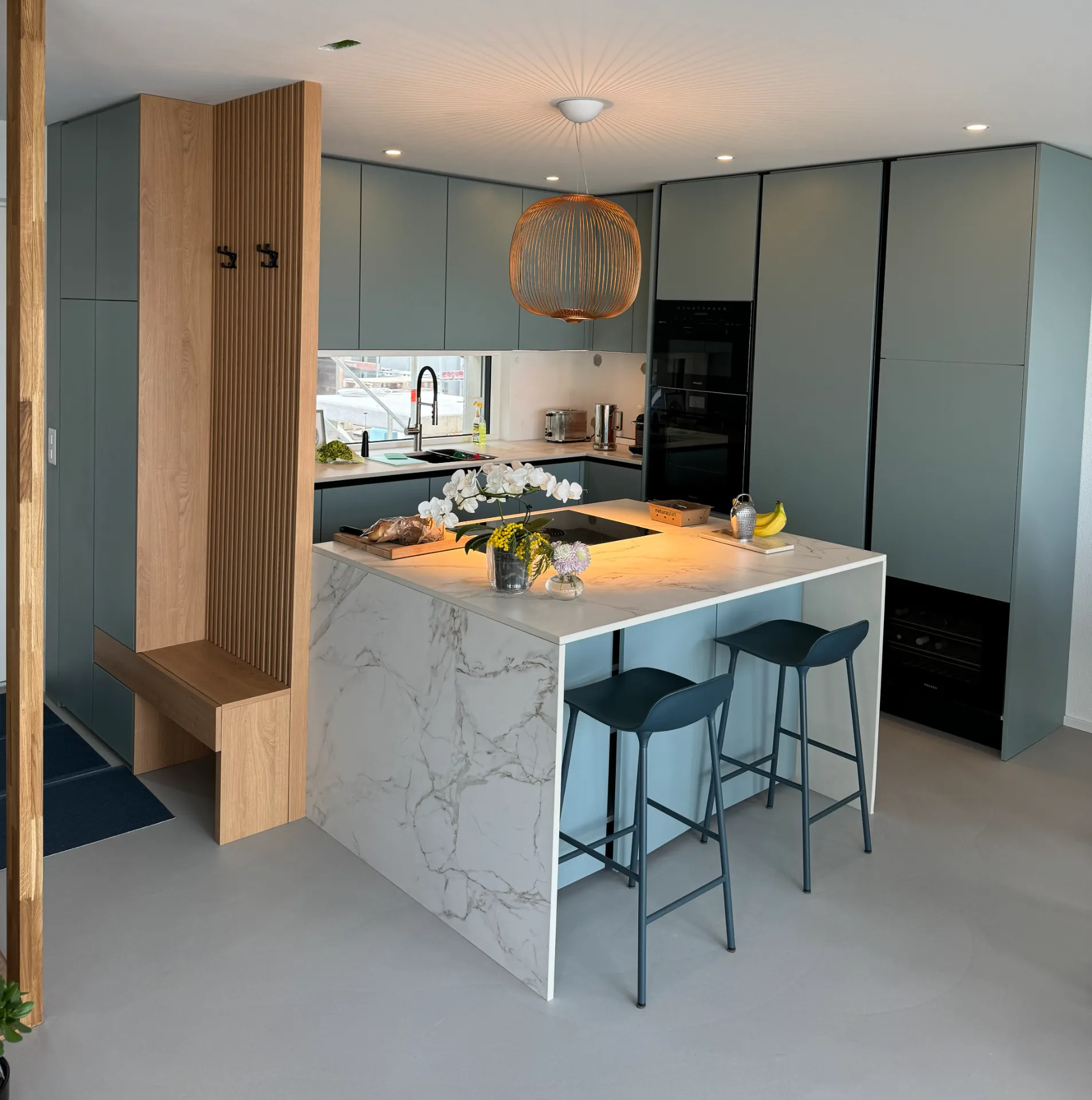 Moderne Einbauküche mit Kochinsel, integrierten Geräten, Holzverkleidung und Barhockern